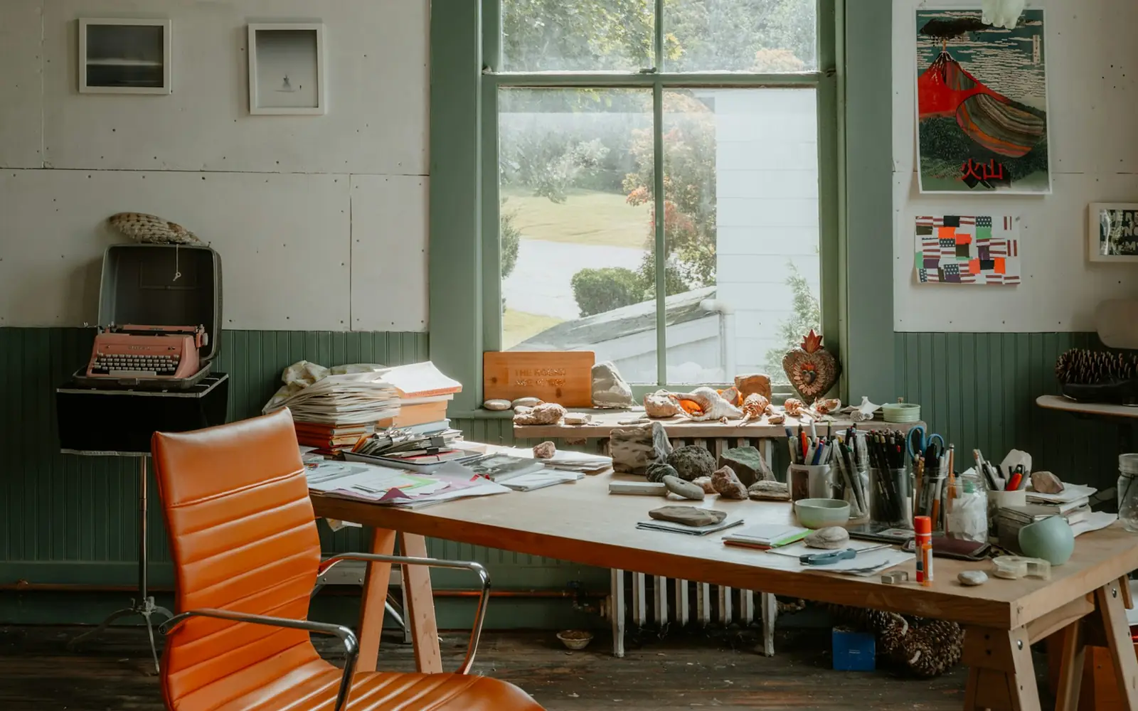 A sunlit artist studio with a working table and pinned studies