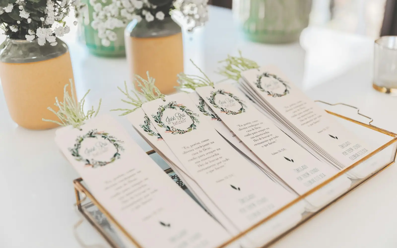Printed botanical invitations arranged with olive foliage